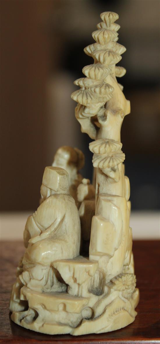 A Chinese ivory group of scholars playing weiqi beneath a pine tree, 19th century, 8.7cm, wood stand, slight repair